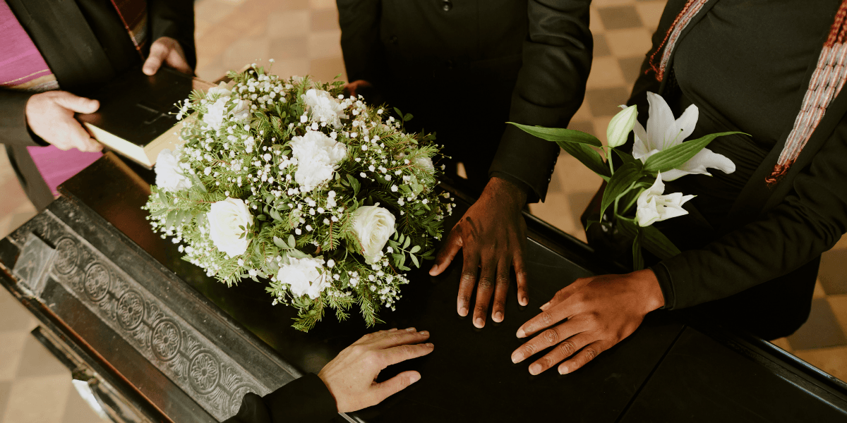 People gathered around a coffin, holding flowers and showing support during a farewell