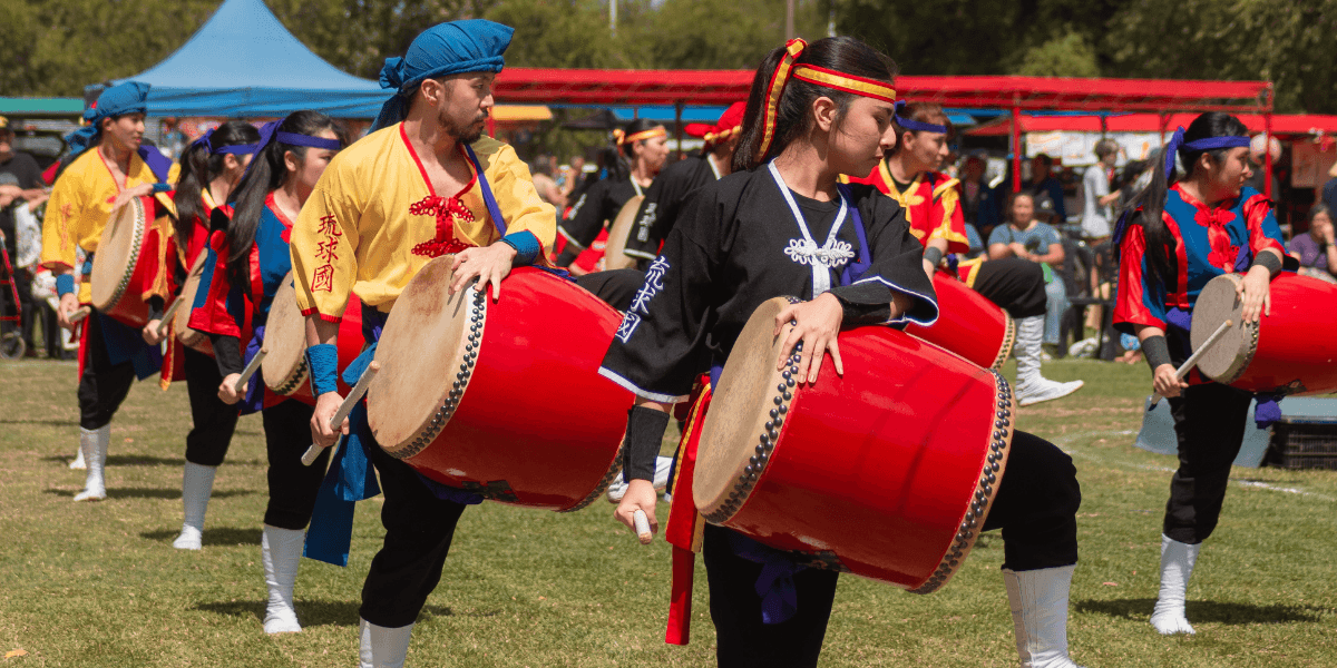 Group of performers drumming in colorful traditional costumes during an outdoor festival