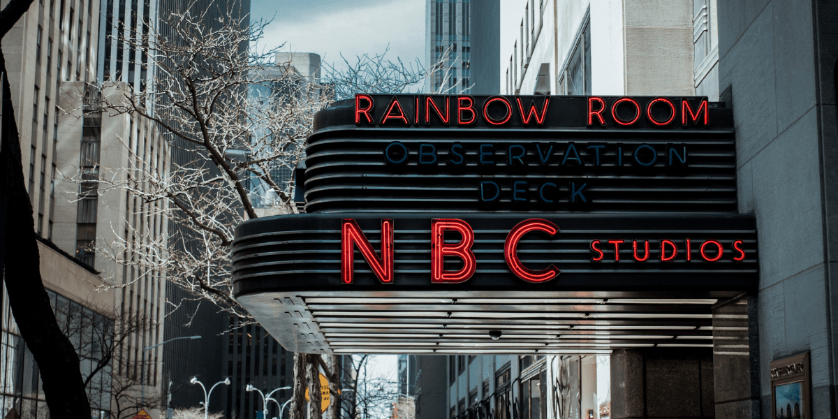 Neon sign for NBC Studios and Rainbow Room above an urban street scene