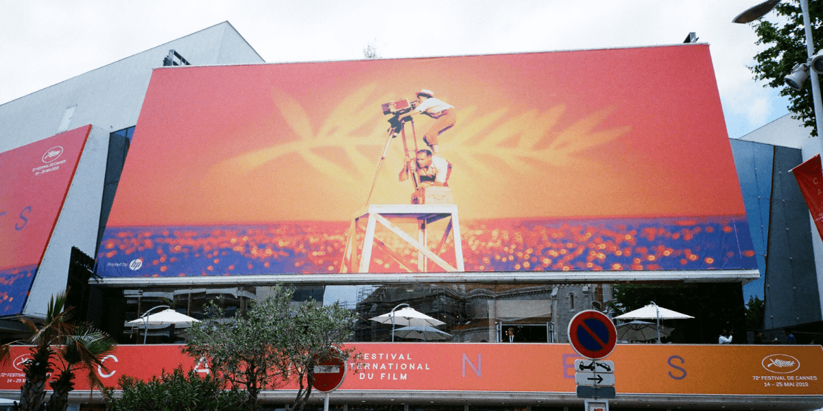 Colorful billboard for the Cannes Film Festival featuring a film camera silhouette against an orange background
