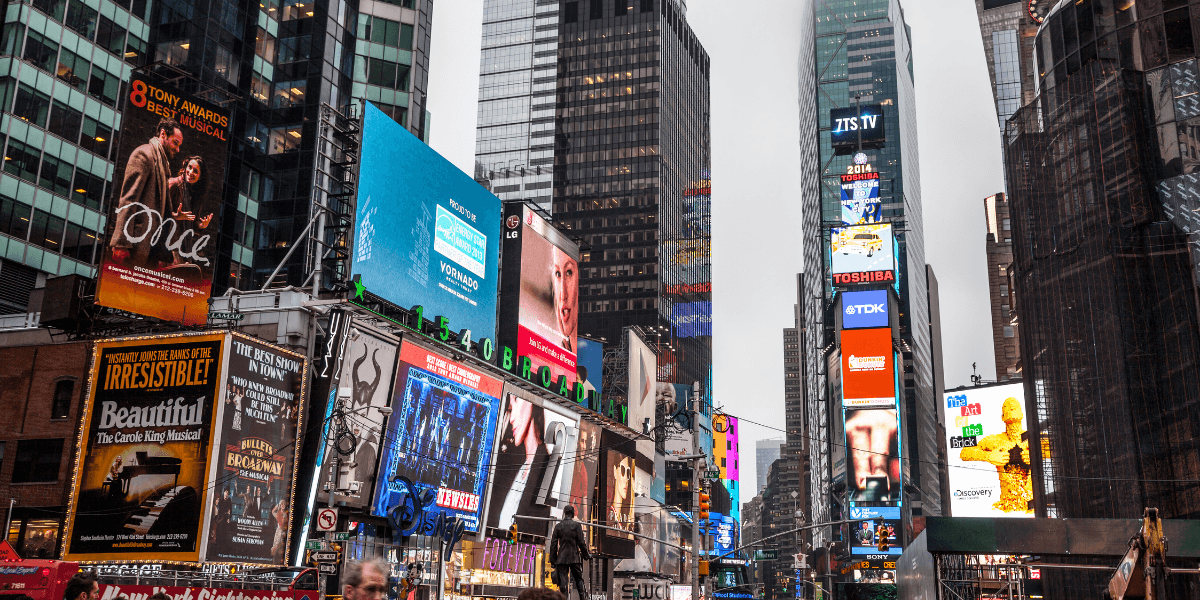 Bustling Times Square filled with bright billboards and crowds on an overcast day