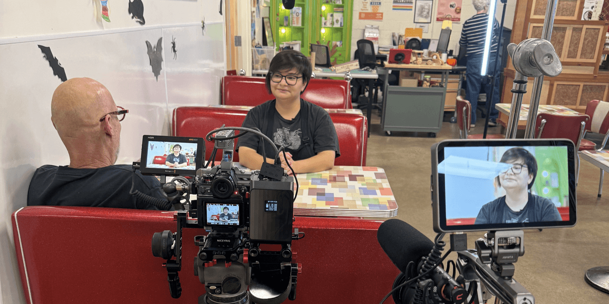 A video interview setup in a diner with two cameras and interviewees at a booth