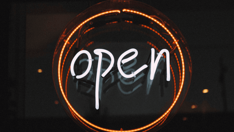 Neon "Open" sign glowing inside a circular orange light against a dark background.