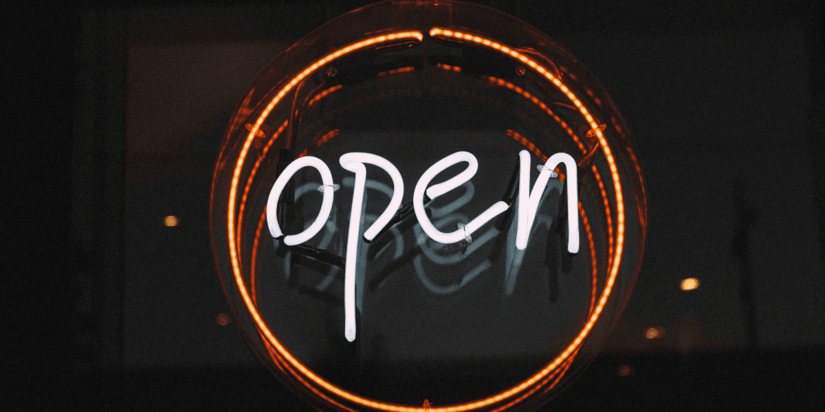 Neon "Open" sign glowing inside a circular orange light against a dark background.