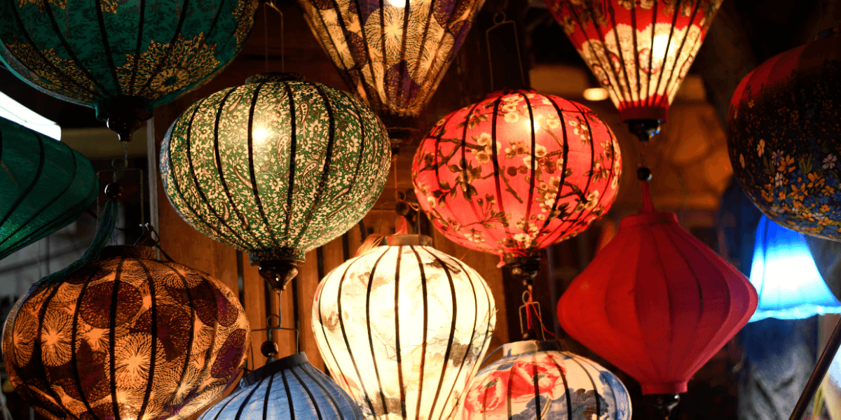 Colorful decorative lanterns hanging indoors with illuminated patterned fabric shades.
