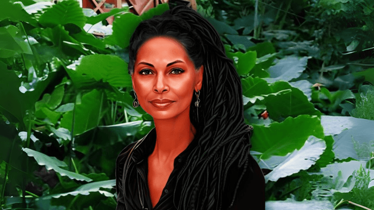 Portrait of a woman with long braids, wearing black, standing in front of lush green tropical plants.