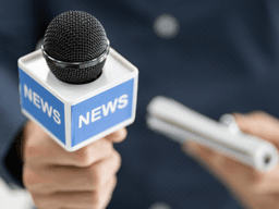 A person holds a microphone labeled "NEWS" and a notepad for reporting.