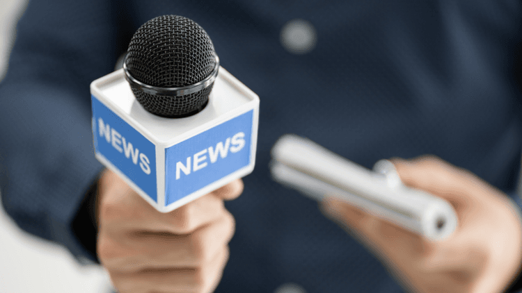 A person holds a microphone labeled "NEWS" and a notepad for reporting.