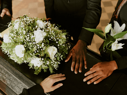 People gathered around a coffin, holding flowers and showing support during a farewell