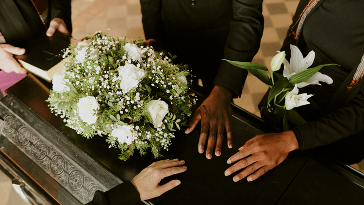 People gathered around a coffin, holding flowers and showing support during a farewell