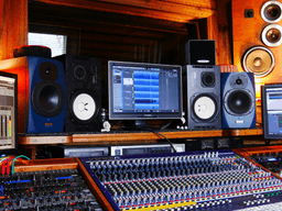 A music production studio featuring mixing consoles, speakers, and monitors in a cozy setting