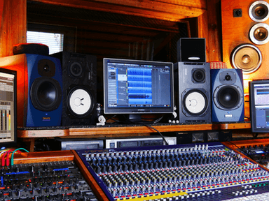 A music production studio featuring mixing consoles, speakers, and monitors in a cozy setting