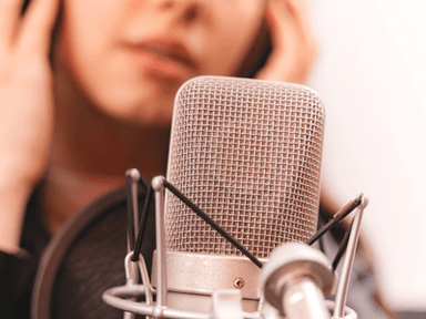 Close-up of a microphone with a blurred person adjusting their headphones in the background