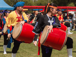 Group of performers drumming in colorful traditional costumes during an outdoor festival