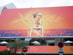Colorful billboard for the Cannes Film Festival featuring a film camera silhouette against an orange background