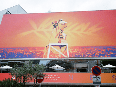 Colorful billboard for the Cannes Film Festival featuring a film camera silhouette against an orange background