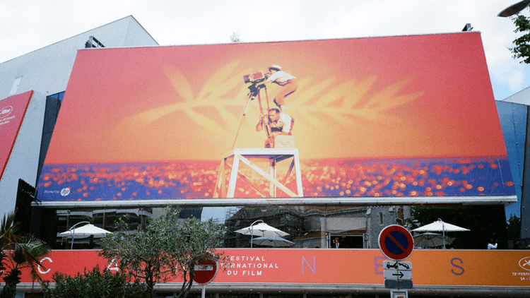 Colorful billboard for the Cannes Film Festival featuring a film camera silhouette against an orange background