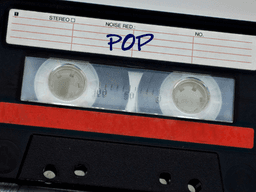 Black cassette tape with a red label marked "POP" on a textured background