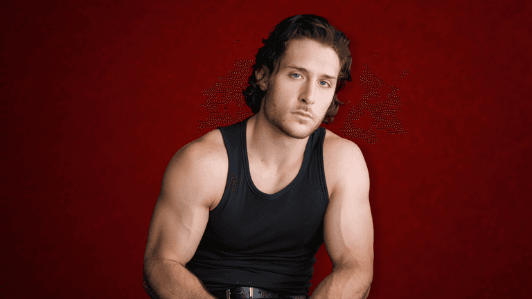 A muscular young man in a sleeveless black shirt poses against a red background