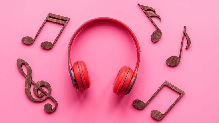Red headphones surrounded by wooden music notes on a pink background