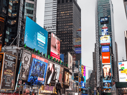 Bustling Times Square filled with bright billboards and crowds on an overcast day