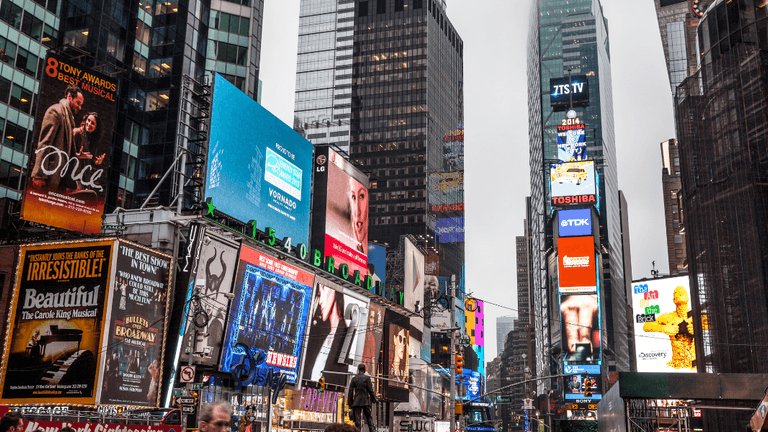 Bustling Times Square filled with bright billboards and crowds on an overcast day