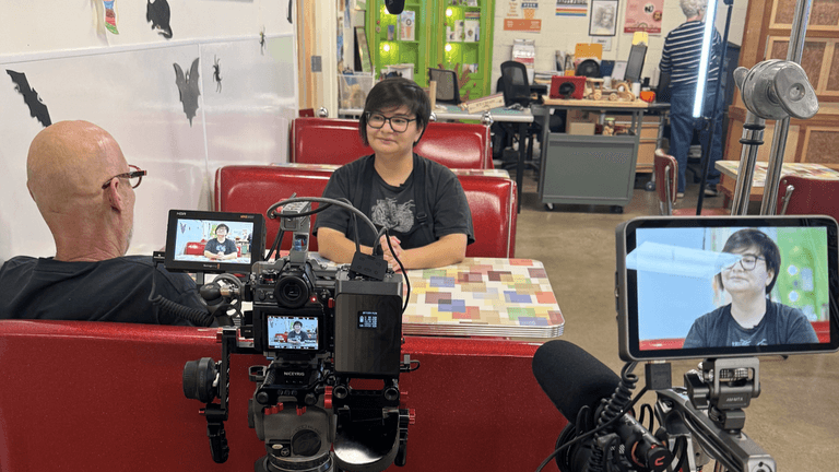 A video interview setup in a diner with two cameras and interviewees at a booth