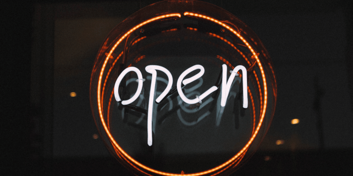 Neon "Open" sign glowing inside a circular orange light against a dark background.