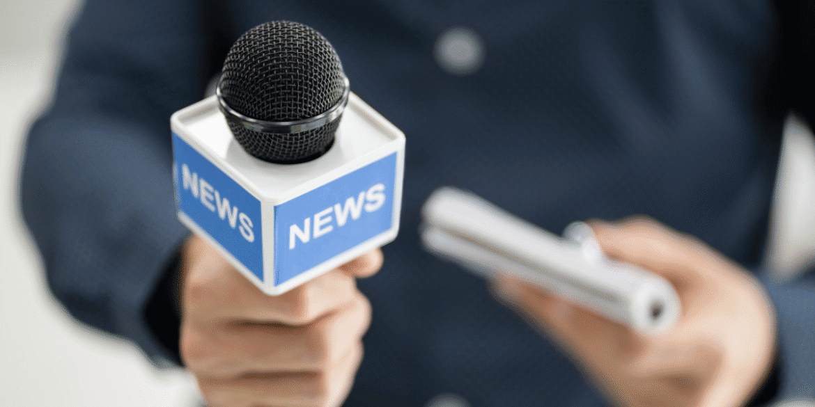 News microphone held toward a person holding a recording device during an interview.